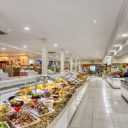אנטליה Sealife Family Resort Hotel מראה חיצוני תמונה The photo shows a spacious dining area, likely a buffet or restaurant, featuring a wide array of colorful food presentations. There are multiple serving stations with neatly arranged dishes, including a variety of salads, appetizers, and desserts. Th