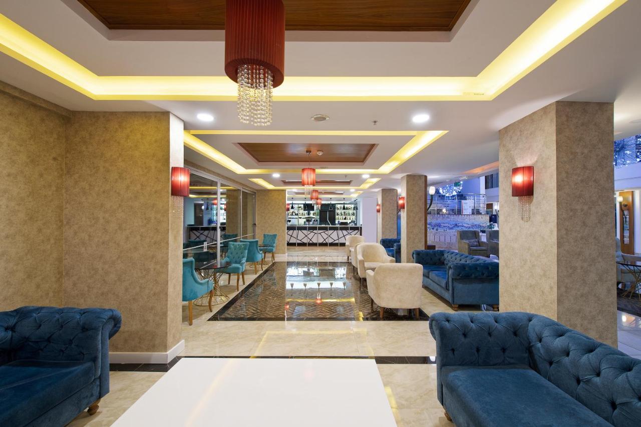 אנטליה Sealife Family Resort Hotel מראה חיצוני תמונה The photo depicts a modern and stylish lobby area. It features a combination of elegant furnishings, including blue and cream-colored sofas arranged around white tables. The floor has a shiny, dark tile that contrasts with the light-colored walls. Am