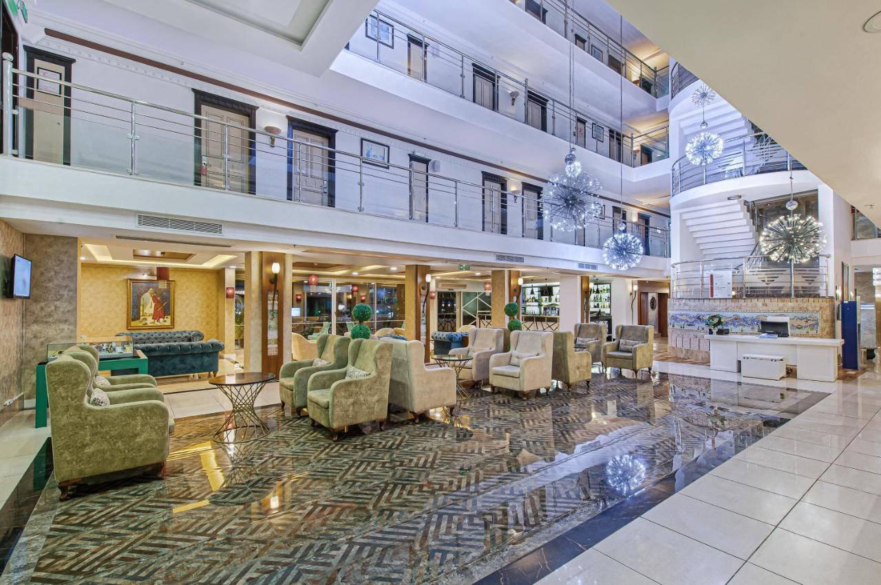אנטליה Sealife Family Resort Hotel מראה חיצוני תמונה The image shows a spacious hotel lobby with a modern and elegant design. The area features a high ceiling with multiple levels, large windows allowing natural light to filter in, and stylish decor elements. There are comfortable seating arrangements 