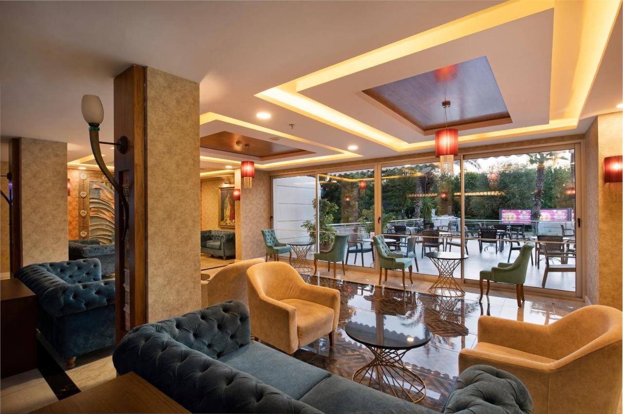אנטליה Sealife Family Resort Hotel מראה חיצוני תמונה The photo shows a modern and stylish lounge or café area. It features comfortable seating arrangements with plush sofas in shades of blue and beige. The interior is well-lit with decorative ceiling lights and elegant pendant lamps hanging above. Larg