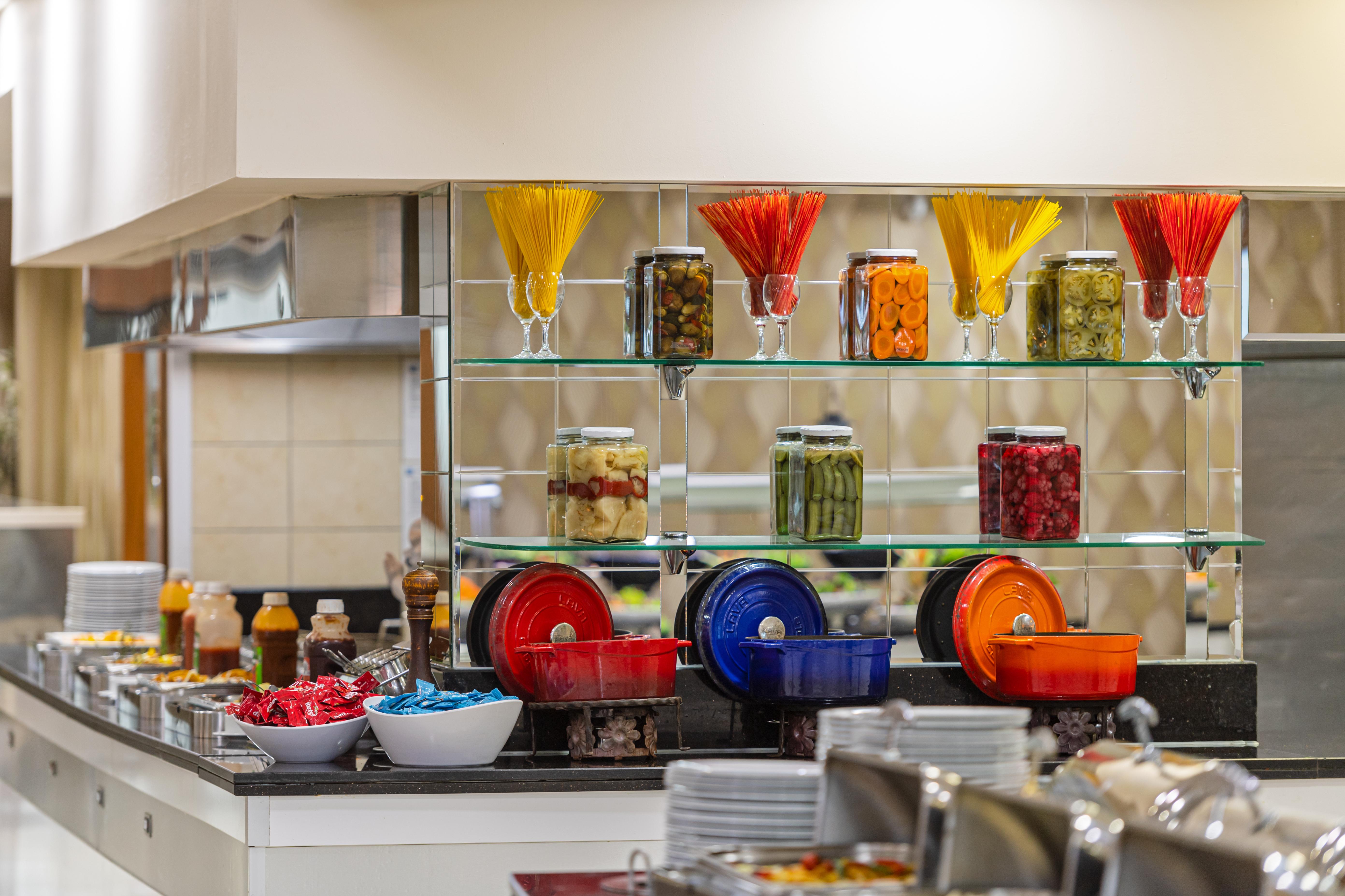 אנטליה Sealife Family Resort Hotel מראה חיצוני תמונה The photo shows a buffet-style food display with a modern and organized arrangement. There are several jars filled with various colorful ingredients, including pasta and preserved fruits or vegetables, displayed on glass shelves. Below, there are bow