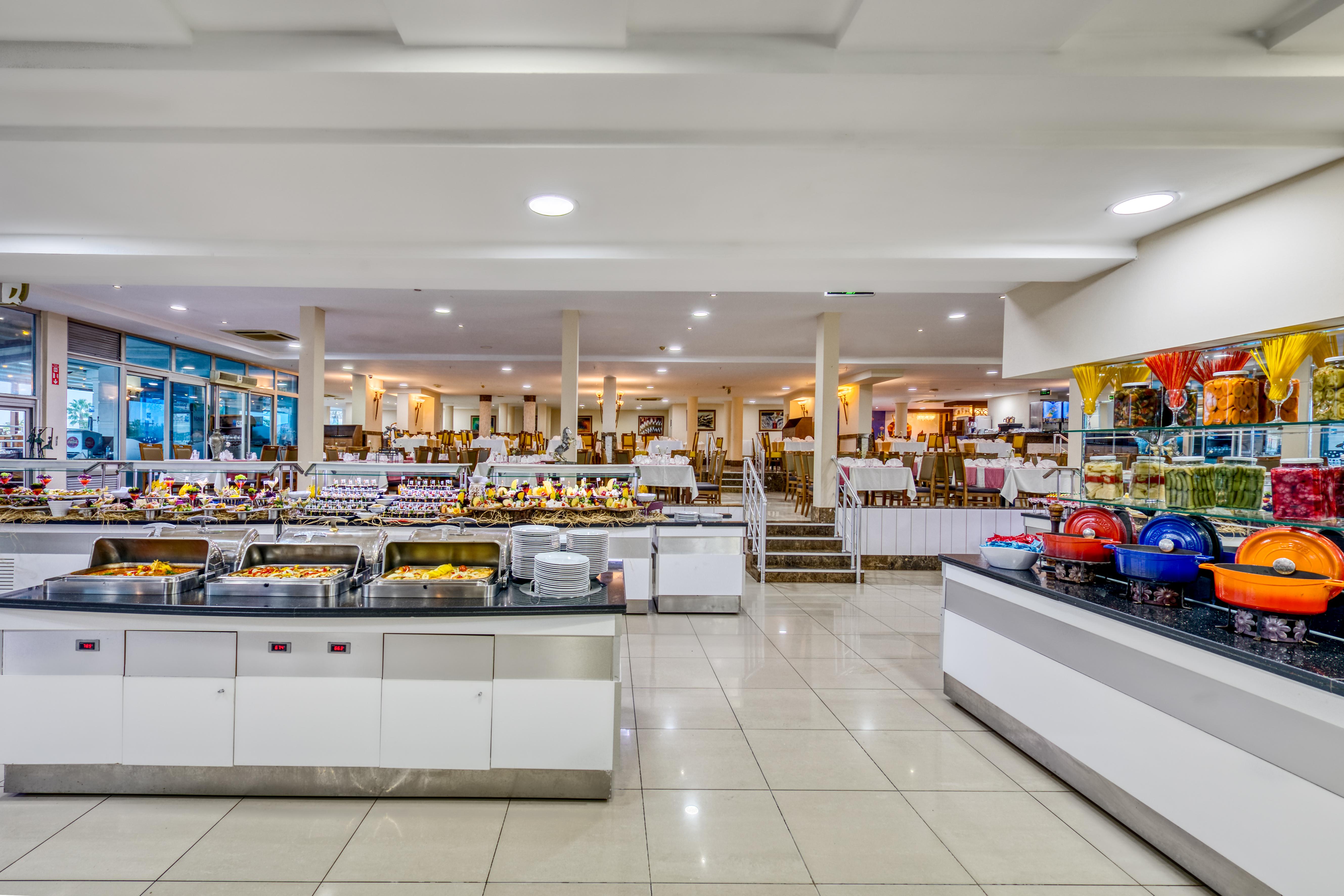 אנטליה Sealife Family Resort Hotel מראה חיצוני תמונה The photo depicts a spacious buffet dining area featuring several food stations. There are multiple serving counters filled with a variety of dishes, showcasing an array of foods typically found in a buffet setting. The space is well-lit, with a mode