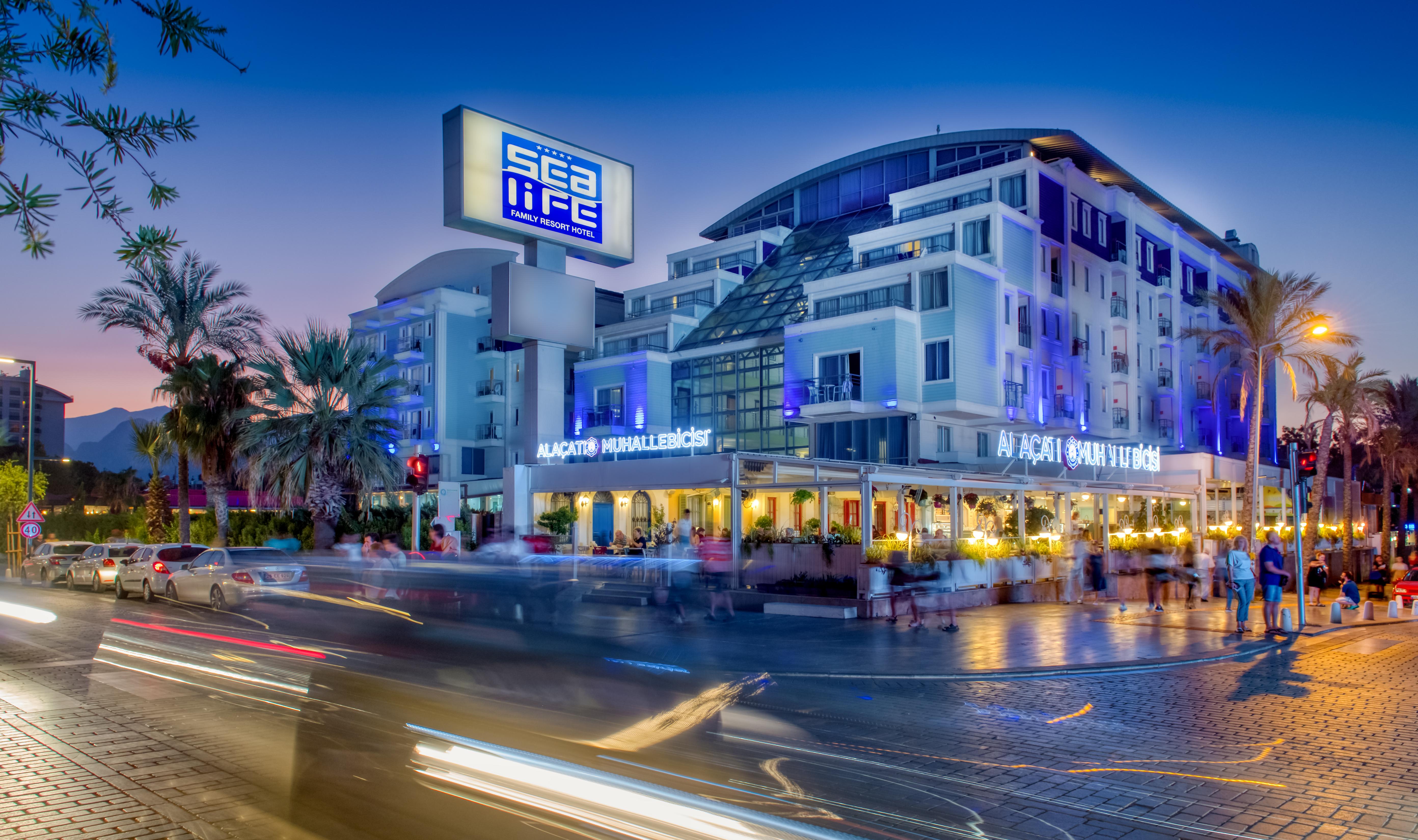 אנטליה Sealife Family Resort Hotel מראה חיצוני תמונה The photo shows a modern building with a prominent sign that reads "Sea Life." The structure has multiple stories and a sleek, contemporary design, featuring large windows. In front of the building, there appears to be a restaurant with outdoor seati