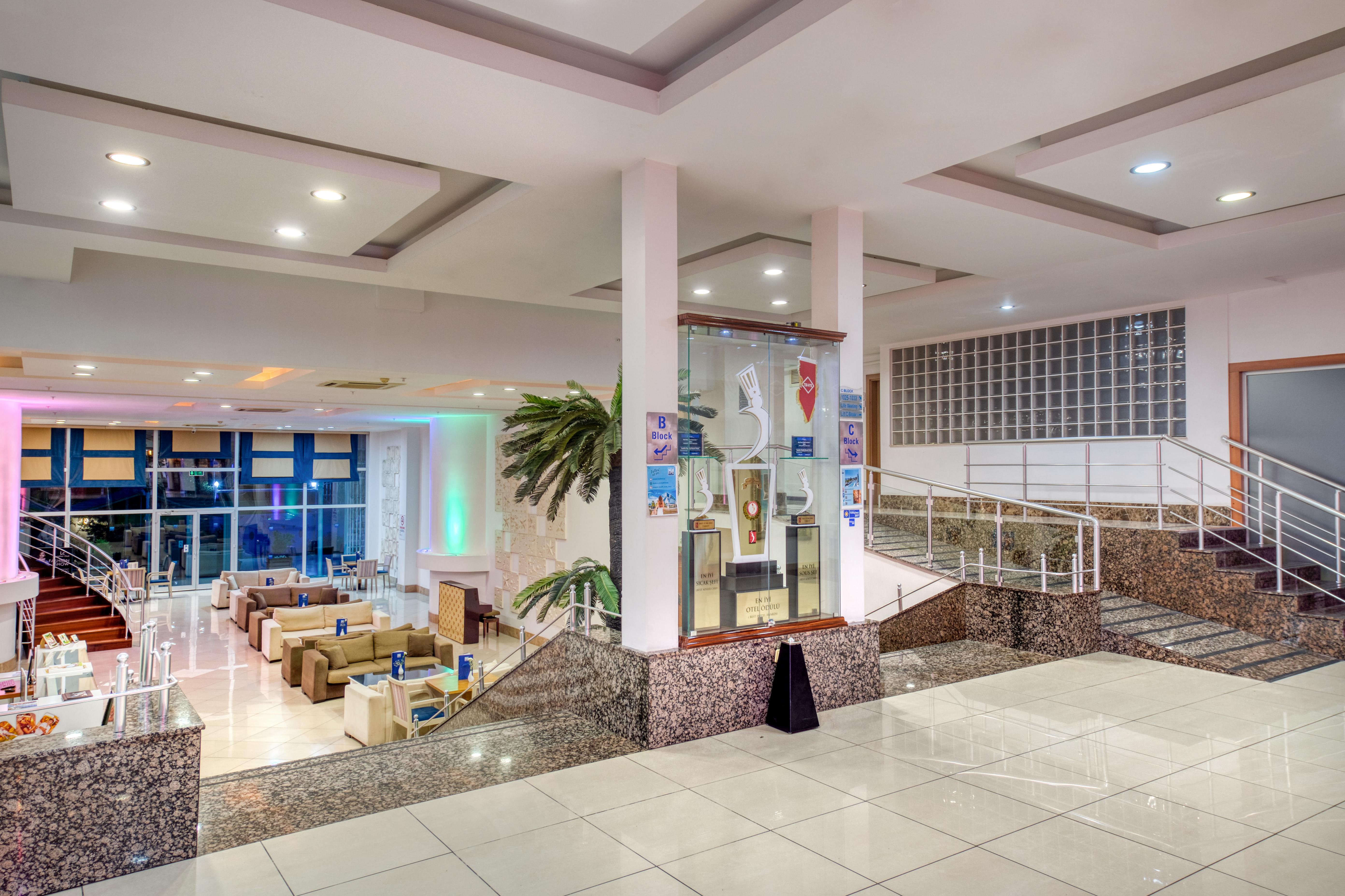 אנטליה Sealife Family Resort Hotel מראה חיצוני תמונה The photo shows a spacious indoor area, likely a hotel or a public building, featuring a modern design. There are several seating arrangements with comfortable couches and chairs visible in the background. The space is well-lit, with ambient lighting