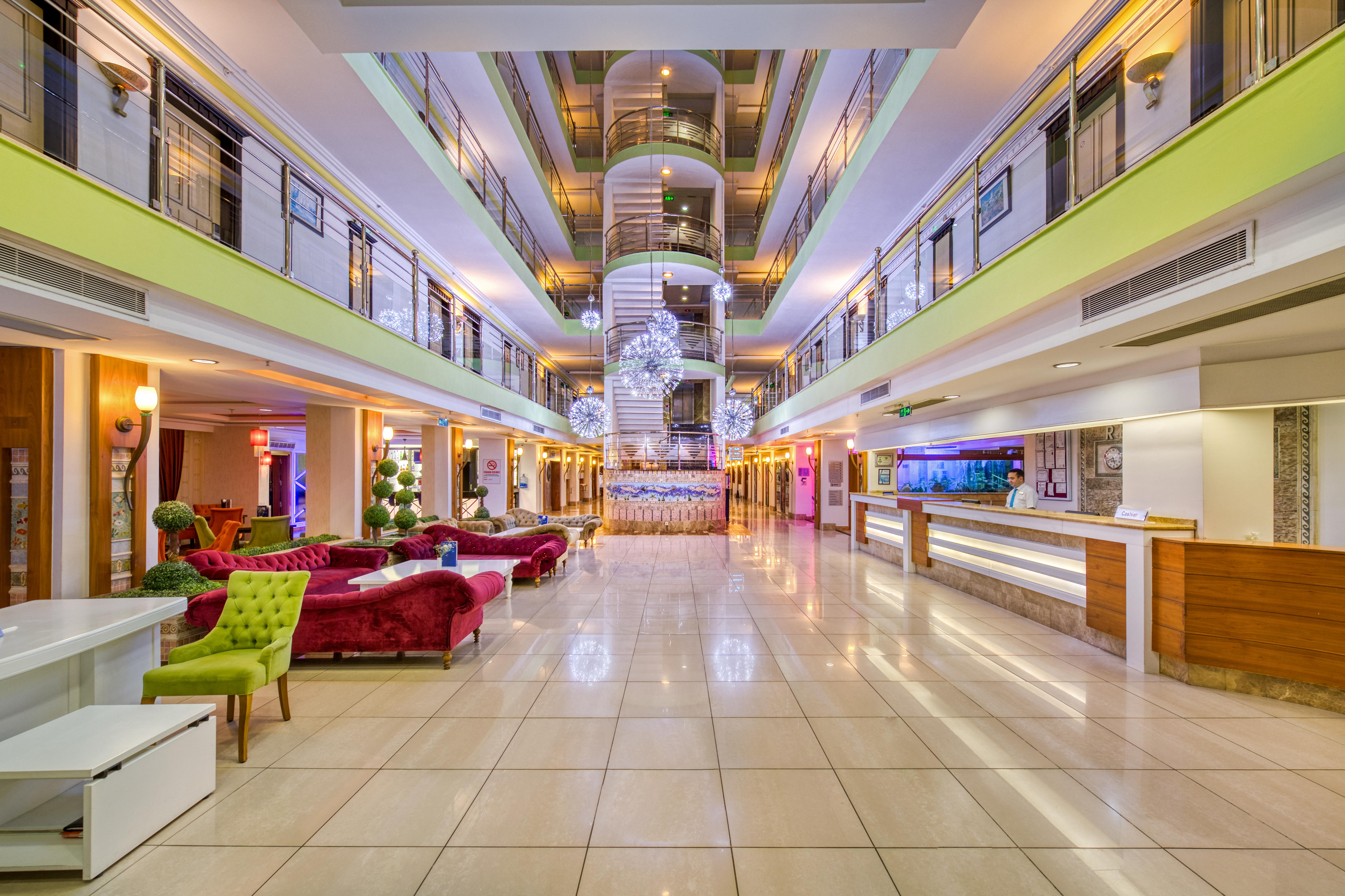 אנטליה Sealife Family Resort Hotel מראה חיצוני תמונה The photo shows the interior of a modern hotel lobby. It features a spacious design with a polished tile floor and various seating areas. Elegant sofas in vibrant colors, such as red and green, are arranged tastefully. In the center, there is a strik