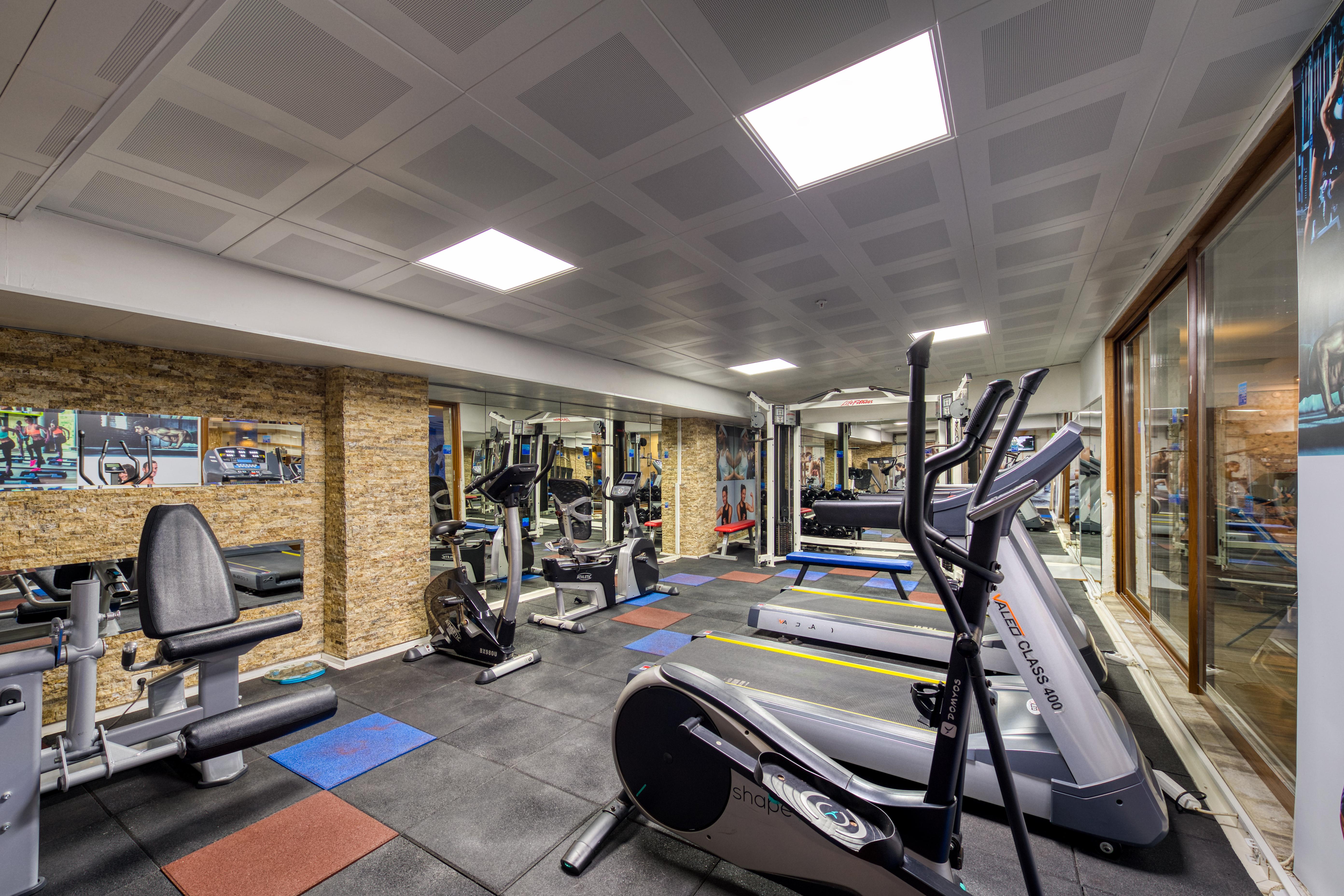 אנטליה Sealife Family Resort Hotel מראה חיצוני תמונה The photo shows an indoor gym space equipped with various exercise machines. There are cardio machines like treadmills and an elliptical trainer, along with strength training equipment. The flooring is made of black mats, and there are a few colored 
