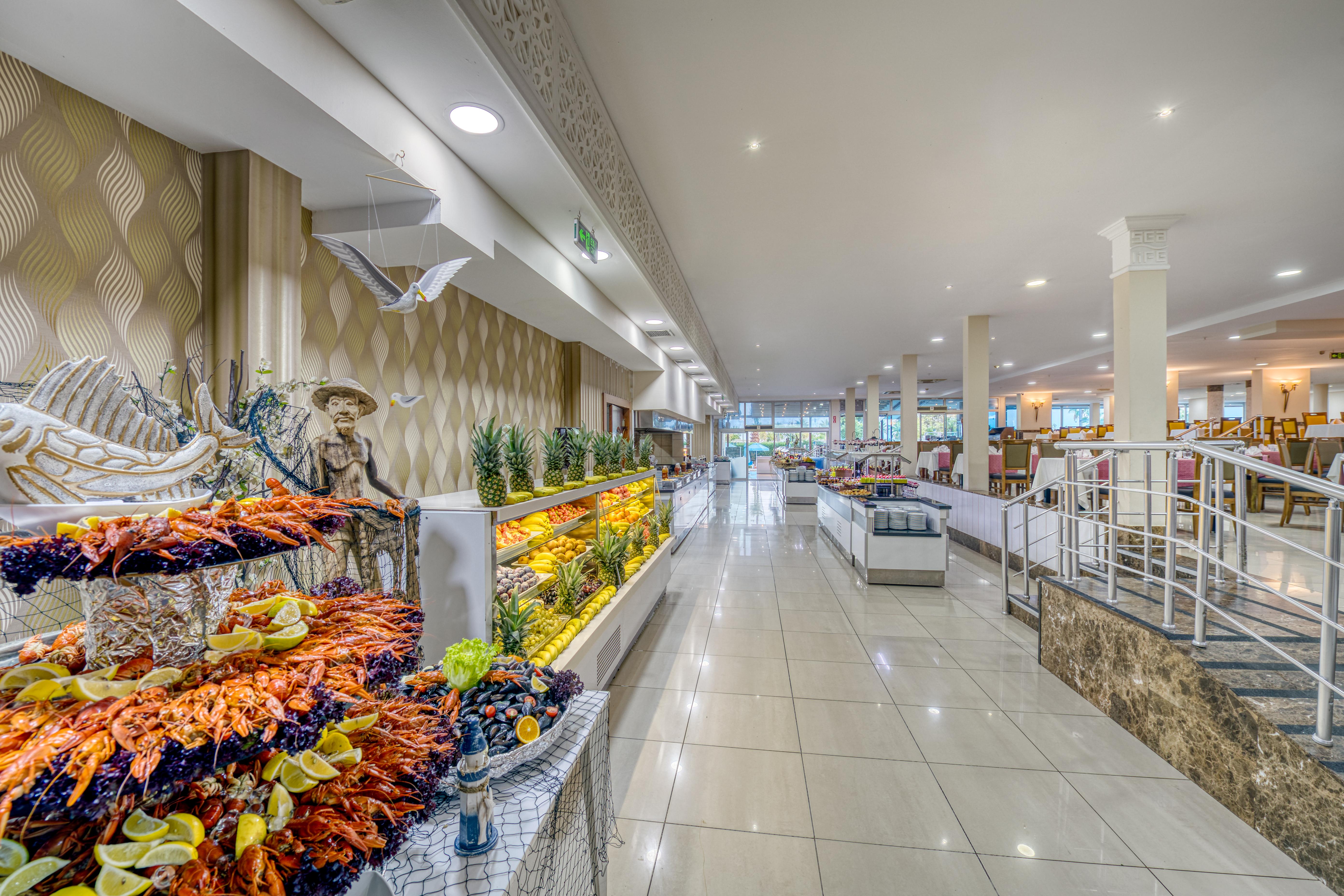 אנטליה Sealife Family Resort Hotel מראה חיצוני תמונה The photo shows the interior of a spacious dining area, likely in a restaurant or buffet. The space features a long corridor with glossy tiled floors and bright, well-distributed lighting. On one side, there are decorative displays of seafood, includ