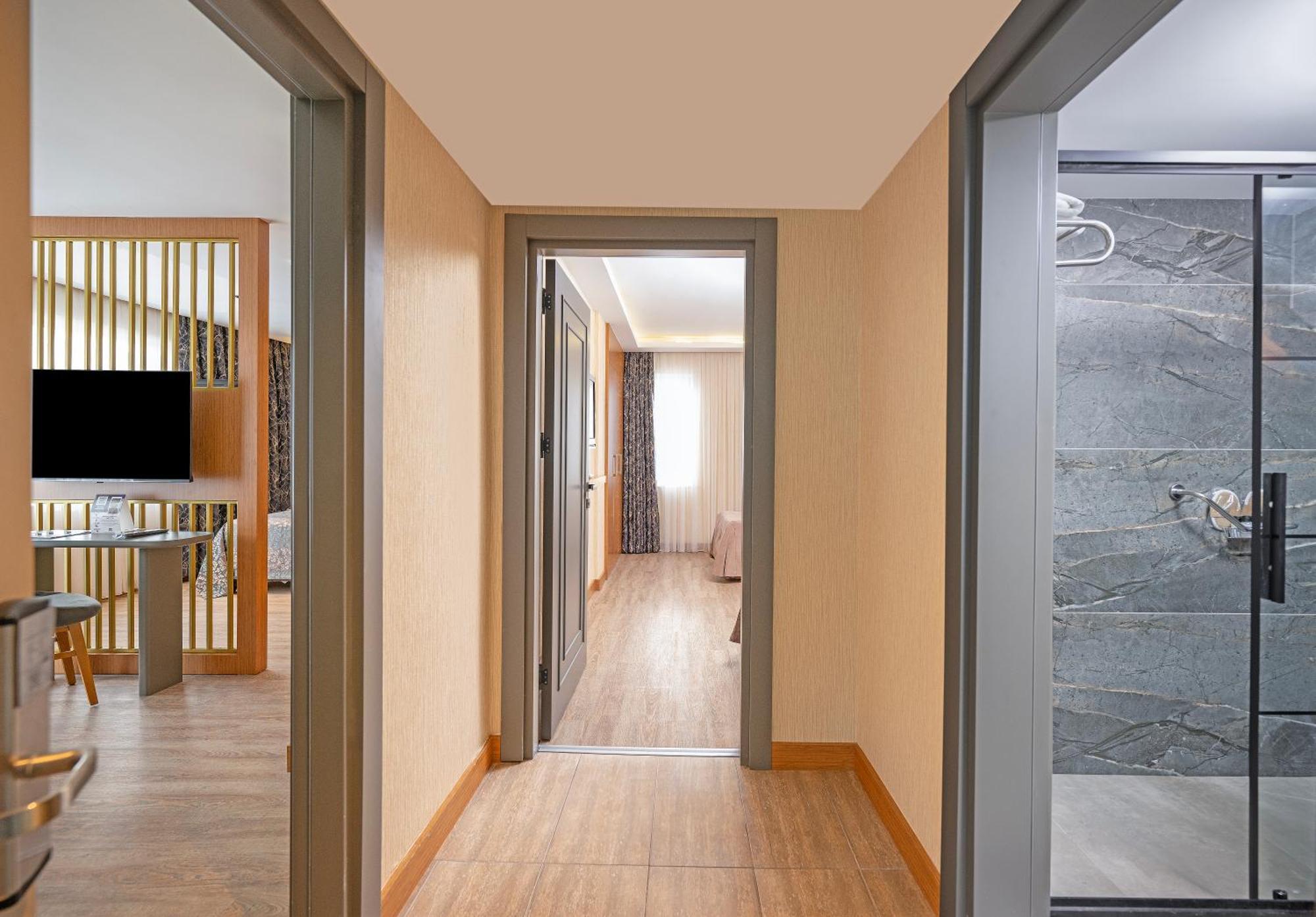 אנטליה Sealife Family Resort Hotel חדר תמונה The image shows a hallway with a few separate rooms visible. On the left side, there's a view of a modern living area with a television and some furniture. At the end of the hallway, light is coming from a window in another room, indicating it may be