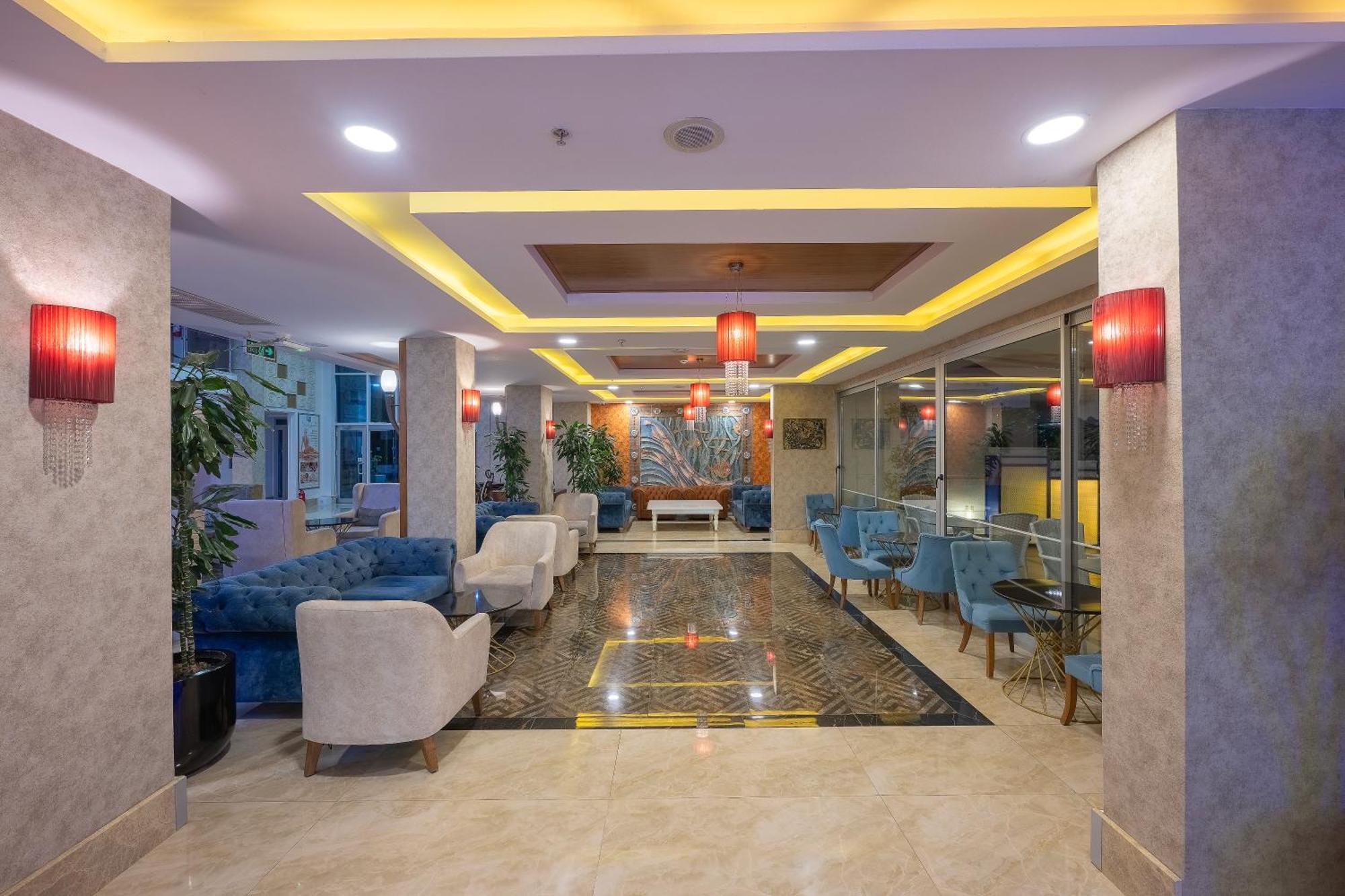 אנטליה Sealife Family Resort Hotel מראה חיצוני תמונה The photo shows a modern lobby area, characterized by stylish decor and a welcoming atmosphere. There are comfortable seating arrangements with blue upholstered chairs and white armchairs. The flooring appears to be a polished stone, complemented by 